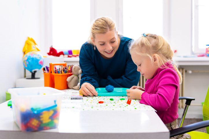 Toddler girl in child playful exercises with her therapist.